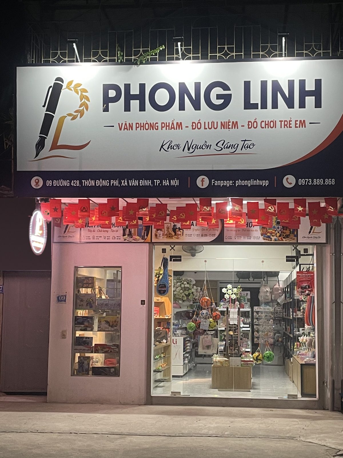 Mặt tiền cửa hàng Phong Linh buổi tối, biển hiệu văn phòng phẩm, đồ lưu niệm, đồ chơi trẻ em